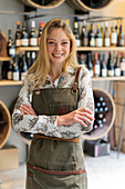 Young woman wearing apron standing in wine shop