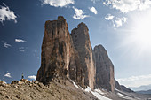 Man below the Drei Zinnen on Paternsattel with a view of the peaks at sun, South Tyrol