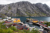 Fischerdorf mit traditionellen Fischerhäusern aus rot und gelb gestrichenem Holz, umgeben von Bergen, Nusfjord, Vestfjord, Lofoten, Norwegen
