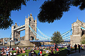 Gruppe von Menschen, die auf dem Rasen vor der Tower Bridge sitzen, London, Grossbritannien, Europa