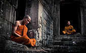 Siem Reap, Cambodia - January 19, 2011: Two monks in their orange robe are sitting and meditating in the Angkor Wat complex.