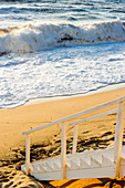 Wooden stairs on sandy beach in the waves