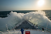 The front of an expedition cruise ship encounters a large wave and sends spray high above the bow at sea in the Caribbean, near Colombia