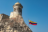 The national flag flies from the city walls of the historic and imposing Castillo San Felipe de Barajas, Cartagena, Bolivar, Colombia, South America