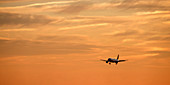 Airplane flying in sky at sunset