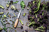 High angle close up of purple sprouting broccoli and knife with wooden handle.
