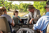 A family of visitors in a safari vehicle with a guide.