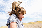 Fünfjähriger Junge mit Erdmännchen auf der Schulter, Kalahari-Wüste, Makgadikgadi-Salzpfannen, Botswana