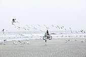 teen girl biking on sandy beach by the ocean, St. Simon's Island, Georgia