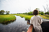 A six year old boy in a jeep on a bridge overlooking marshes and water.