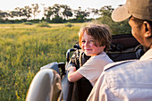 Lächelnder 6-jähriger Junge, der einen Safari-Jeep steuert, Botswana
