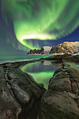Magisches Nordlicht über dem Berg 'Teufelszähne', Reflexionen im Wasser entlang des Ersfjords, Senja, Nordnorwegen, Europa