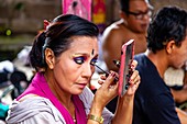 A Woman Applies Make Up Before Performing In A Traditional Balinese Barong and Kris Dance Show, Batabulan, Bali, Indonesia.
