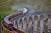 Jacobite express steam train crossing the Glenfinnan Viaduct on route from Mallaig to Fort William, Lochaber, West Highlands, Scotland