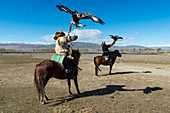 Zwei kasachische Adlerjäger im Sagsai-Tal im Altai-Gebirge auf dem Weg zum jährlichen Golden Eagle Festival (Adlerjägerfest) in der Nähe der Stadt Ulgii (Ölgii) in der Provinz Bajan-Ölgii in der Westmongolei