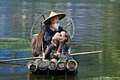Cormorant Fisherman resting on Bamboo Raft\nGuilin Region\nGuangxi, China\nLA008337