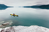 Frau unterwegs mit Kajak, unberührtes Wasser von Muir Inlet, bewölkter Himmel in der Ferne, Glacier-Bay-Nationalpark, Alaska