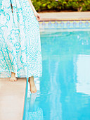 Caucasian woman dipping foot into swimming pool
