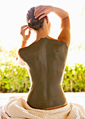 Caucasian woman with mud treatment on back