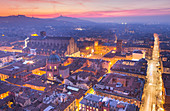 Erhöhtes Stadtbild der Altstadt von Bologna vom Asinelli-Turm in der Abenddämmerung mit der Kirche San Luca im Hintergrund. Bologna, Emilia Romagna, Italien, Europa