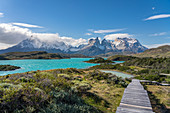 Boardwalk with Lake Pehoé and Paine Horns in the background, on a windy summer day. Torres del Paine National Park, Ultima Esperanza province, Magallanes region, Chile.