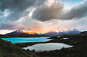 Pehoé-See und Regenbogen im Morgengrauen, mit Cerro Paine Grande, Hörnern von Paine und Cerro Paine im Hintergrund mit Nebel bedeckt, Nationalpark Torres del Paine, Provinz Ultima Esperanza, Region Magallanes, Chile