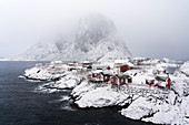 Hamnoy Dorf im Schnee, mit dem Gipfel von Festheltinden im Hintergrund, Moskenes, Nordland, Nordnorwegen, Norwegen