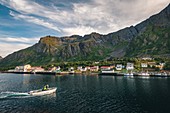 Fischerboot beim Einlaufen in den Hafen in der Stadt Gryllefjord, Umgeben von Bergen, Senja, Norwegen