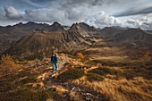 Wanderer auf einem Weg, der zum Gipfel des Valette De Prals führt, Herbstliche Farben, Mercantour-Nationalpark, Saint-Martin-Vesubie, Provence-Alpes-Côte-D'azur, Alpes-Maritimes, Frankreich
