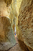 Woman hiking through canyon Gorges de Regalon, Gorges de Regalon, Luberon Natural Park, Vaucluse, Provence-Alpes-Cote d'Azur, France