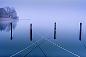 Ropes on wooden posts in the abandoned harbor in winter in Lake Starnberg, Seeseiten, Bavaria, Germany