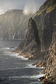 Steilküste im Westen der Insel Vágar mit dem Wasserfall Bøsdalafossur und der Felsnadel Geitaskoradrangur, Färöer Inseln, Dänemark