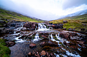 Bachlauf und kleiner Wasserfall auf der Insel Streymoy mit wolkigem Himmel, Färöer Inseln