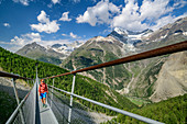 Woman walks over Kuonen suspension bridge, longest suspension bridge in the Alps, Weißhorn in the background, Kuonen suspension bridge, Europaweg, Randa, Walliser Alps, Valais, Switzerland