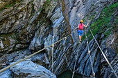 Woman commits rope bridge on Möllschlucht via ferrata, Möllschlucht, Glockner Group, Hohe Tauern, Hohe Tauern National Park, Carinthia, Austria