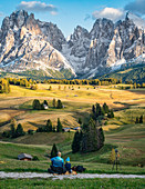 Father and son enjoy the sunset with a view of the snow-covered Langkofel and Plattkofel on the Alpe di Siusi in South Tyrol, Italy