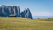Hütten vor einer massiven Bergwand auf der Seiser Alm in Südtirol, Italien