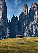 Einsame Hütte vor einer massiven Bergwand auf der Seiser Alm in Südtirol, Italien