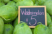 Watermelons on display with a sign in Rarotonga market, Cook Islands.Watermelons are mostly water, about 92 percent , but It soaked with nutrients. Food background and texture. Copy space