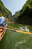 Chinesische Männer rudern ein traditionelles Sampan-Boot in der Nähe von Badong am Shennong-Strom, einem Nebenfluss des Jangtse an der Wu-Schlucht (Drei Schluchten) in China.