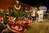 Frauen in einem regionalen Kostüm und riesigen Puppen, gekleidet als Braut und Bräutigam während einer Calenda, einer Prozession durch die Straßen der Innenstadt von Oaxaca, die eine Hochzeit in der Stadt Oaxaca de Juarez, Oaxaca, Mexiko feiert.