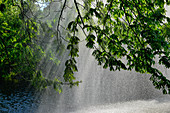 Springbrunnen mit Wassertropfen im Gegenlicht in einem Park in Wien, Österreich