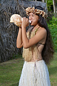 Polynesische Cook-Insulanerin beim Blasen von Muschelschalen in Rarotonga, Cookinseln