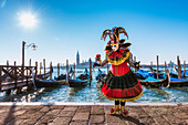 Typical mask of Carnival of Venice in Riva degli Schiavoni with St. George's island in the background, Venice, Veneto, Italy