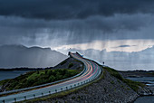 Gewitterwolken über Autolichtspuren auf Storseisundet Brücke, Atlantikstraße, mehr og Romsdal Grafschaft, Norwegen