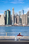 A guy looking at Manhattan from Brooklyn district. Brooklyn, New York City.