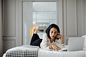 Businesswoman using smartphone and laptop in suite