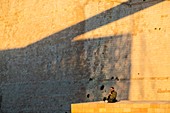 France, Bouches du Rhone, Marseille, a clarinet player in front of Fort Saint Jean at sunset with the shadow of the bridge