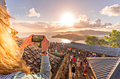 Frau macht Bilder mit Smartphone während der Sonnenuntergangsparty, Shirley Heights, Antigua, Antigua und Barbuda, Westindische Inseln, Karibik, Mittelamerika