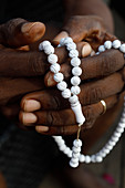 Nahaufnahme der Hände des afrikanischen muslimischen Mannes, der mit islamischen Gebetsperlen (Tasbih), Togo, Westafrika, Afrika betet